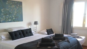 A hotel room with two beds, a large painting on the wall, a floor lamp, and a window with curtains. - 4 bedrooms Villa with pool, Sea view - 3 min walk to Binibeca vell (Binibequer)