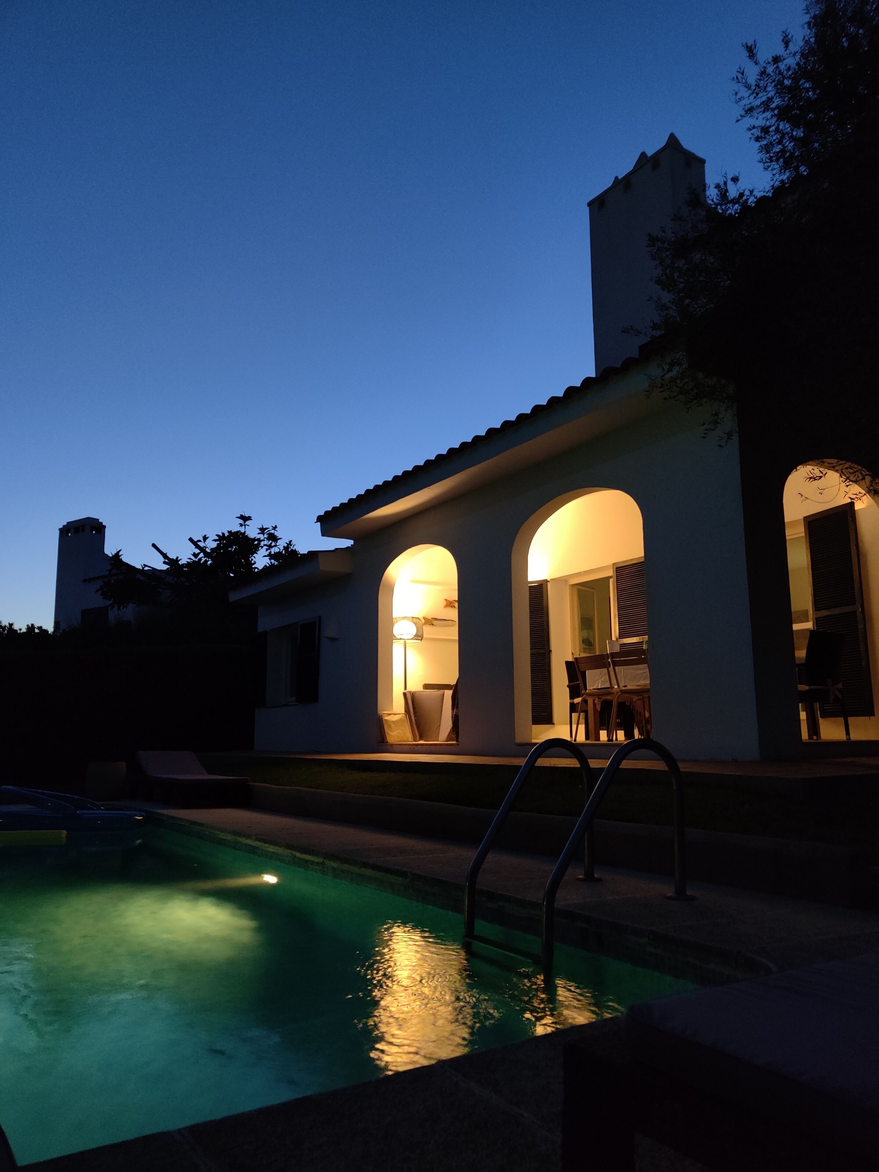 A modern house with a swimming pool, featuring a patio with outdoor furniture and a staircase leading to the entrance.