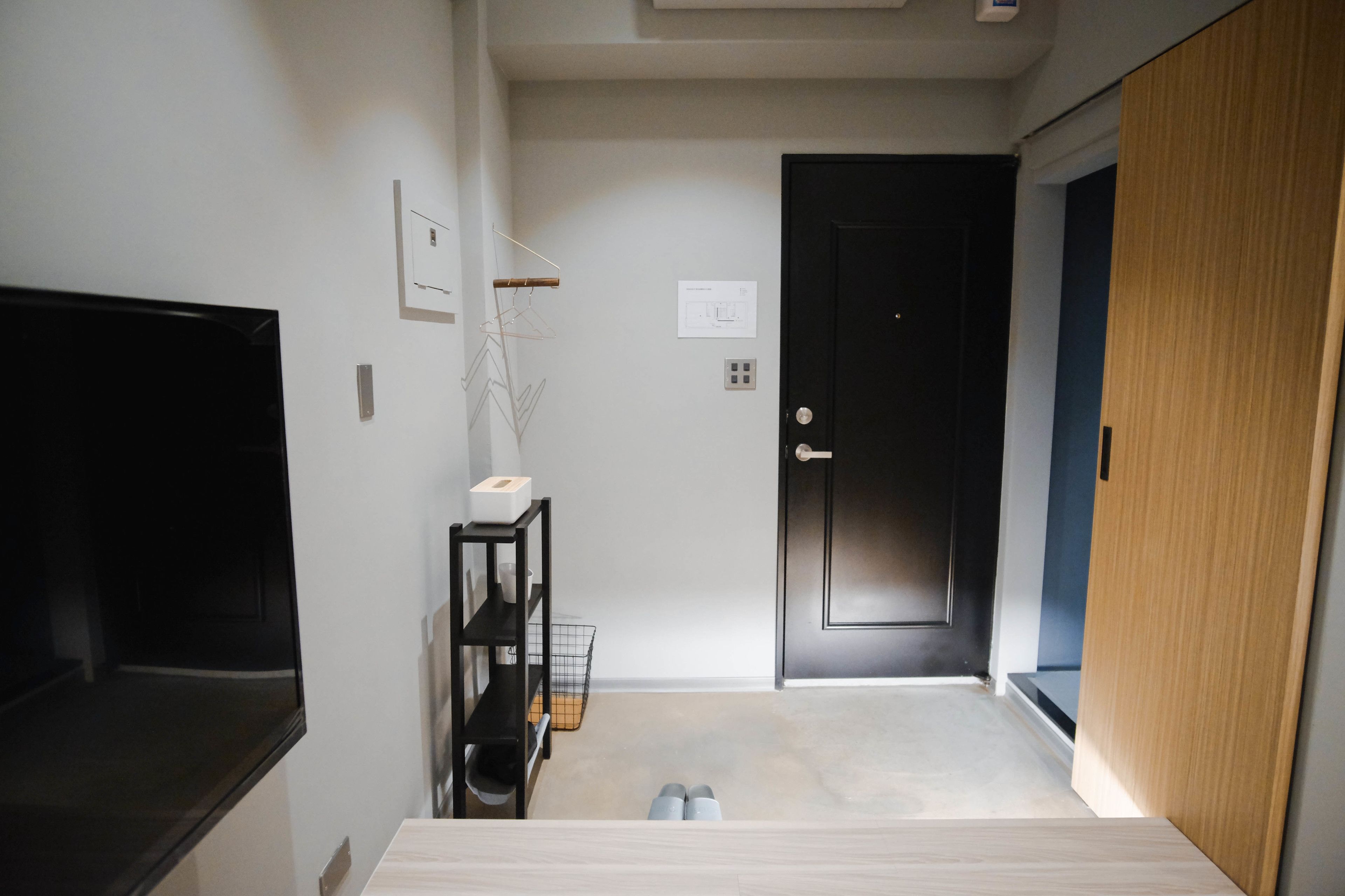 A modern, minimalistic room with a flat-screen TV, a small table, and a door.