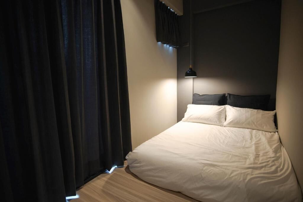 Ein Schlafzimmer mit einem Bett, Vorhängen und einer Pendelleuchte.