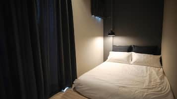 Ein Schlafzimmer mit einem Bett, Vorhängen und einer Pendelleuchte.