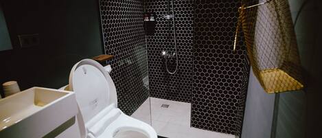 A modern bathroom with a white toilet, a sink, and a shower area with a hexagonal tile pattern.