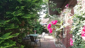 Une terrasse avec un sol en briques, une table et des chaises.