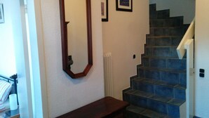 Un escalier aux marches bleues, un banc en bois, un miroir et des tableaux encadrés accrochés au mur.