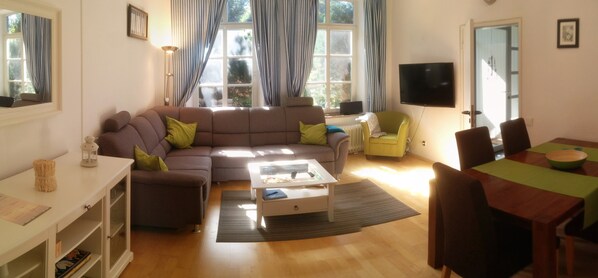 A living room with a sofa, coffee table, and dining area with chairs and a table.