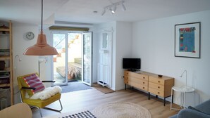 A modern living room with a sofa, a yellow chair, a television, a wooden dresser, and a large window. - Cozy city apartment in Schwäbisch Hall (Schwäbisch Hall)