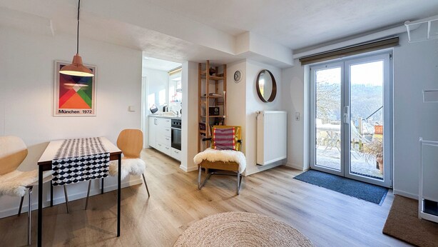 A modern living room with a dining table, chairs, a sofa, a fireplace, and a view through a glass door. - Cozy city apartment in Schwäbisch Hall (Schwäbisch Hall)