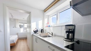 A modern kitchen with a built-in oven, a coffee maker, and a window with a view. - Cozy city apartment in Schwäbisch Hall (Schwäbisch Hall)