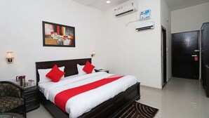 A hotel room with a large bed, a nightstand, a chair, a wall-mounted air conditioner, and a door. - OYO 131 Nhu Phuc Hotel (Ho Chi Minh City)