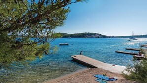 A clear lake with boats, a dock, and a beach with towels and shoes. - Lovely home in Rogoznica (Rogoznica)