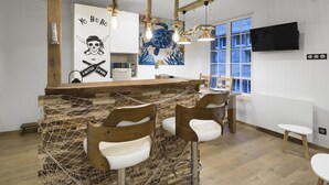 Une cuisine moderne avec un îlot central en bois, des tabourets de bar et une fresque murale.