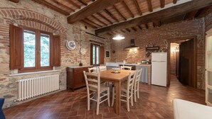 A rustic kitchen with exposed brick walls, wooden beams, and a tiled floor. - Nice home in Civitella Marittima GR (Civitella Marittima GR)
