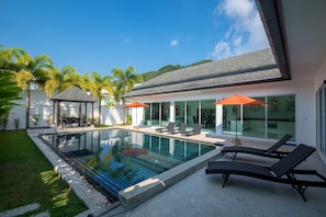 A modern house with a swimming pool, outdoor seating, and a covered patio area. - Kamala Contemporary 3 Bedrooms Pool Villa (Kamala)