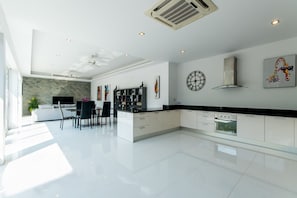 Modern kitchen and dining area with sleek cabinetry, black countertop, and stainless steel appliances.