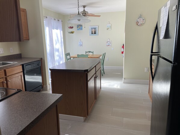 A kitchen with wooden cabinets, a built-in oven, a refrigerator, and a dining area with chairs and a table.