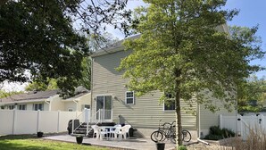 Une maison à deux étages avec un patio couvert, un petit jardin et un vélo garé à l’extérieur.