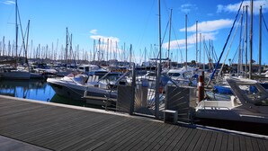 Ein Yachthafen mit zahlreichen angossenen Booten, einem hölzernen Deck und einem strahlend blauen Himmel.