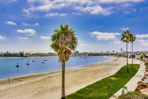 Enjoy a serene beachside retreat with sailboats anchored offshore and palm trees lining the shore.
