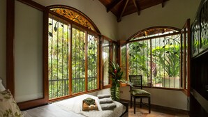 Un dormitorio con un ventanal grande, una cama, una silla y una planta en maceta.