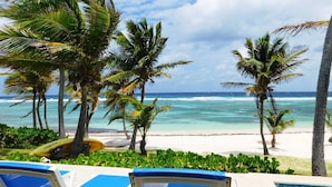 Une vue sur la piscine, avec des chaises longues et une vue sur l’océan.