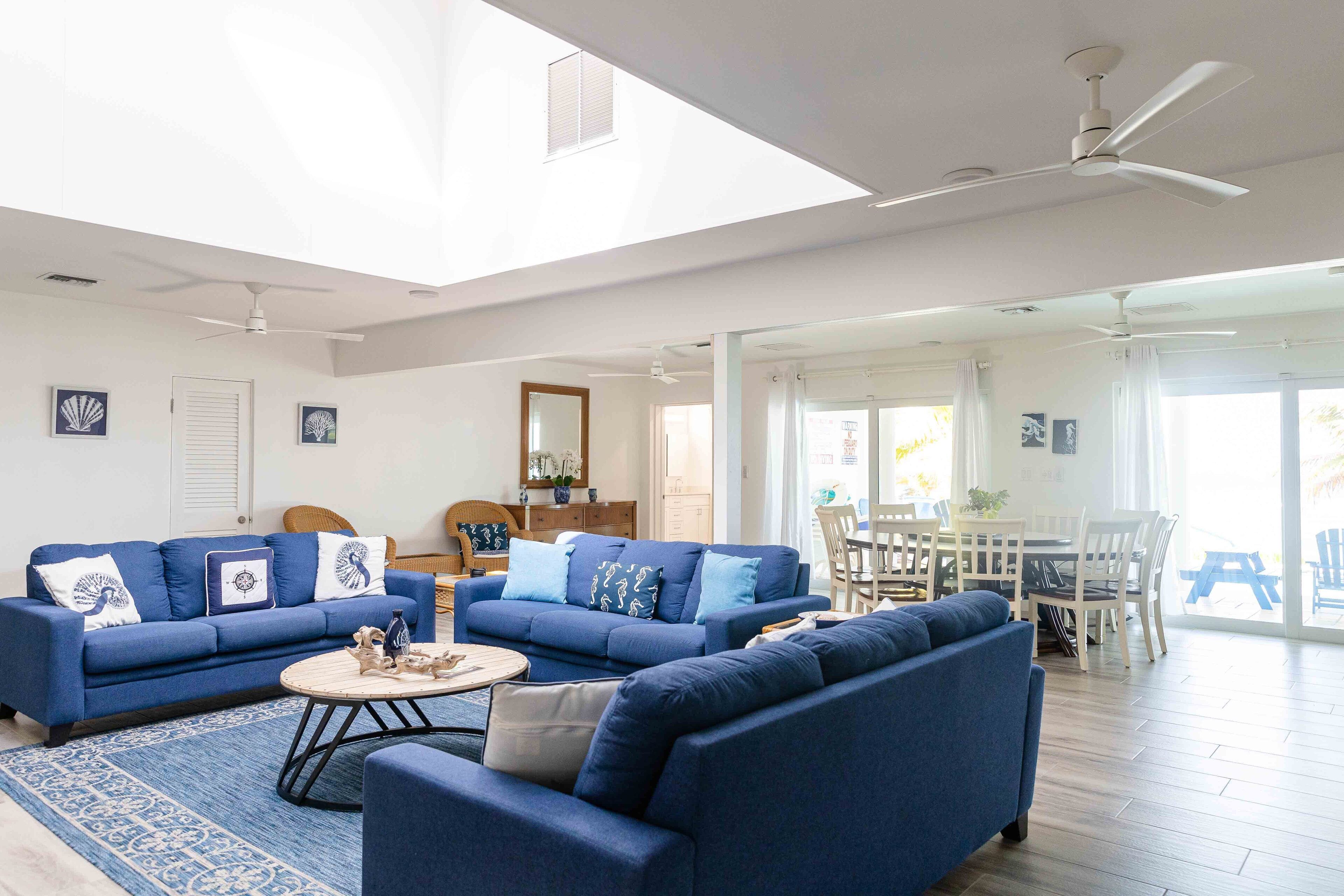 Un salon spacieux avec un plafond haut, deux canapés, une table basse et un coin repas comprenant une table et des chaises.