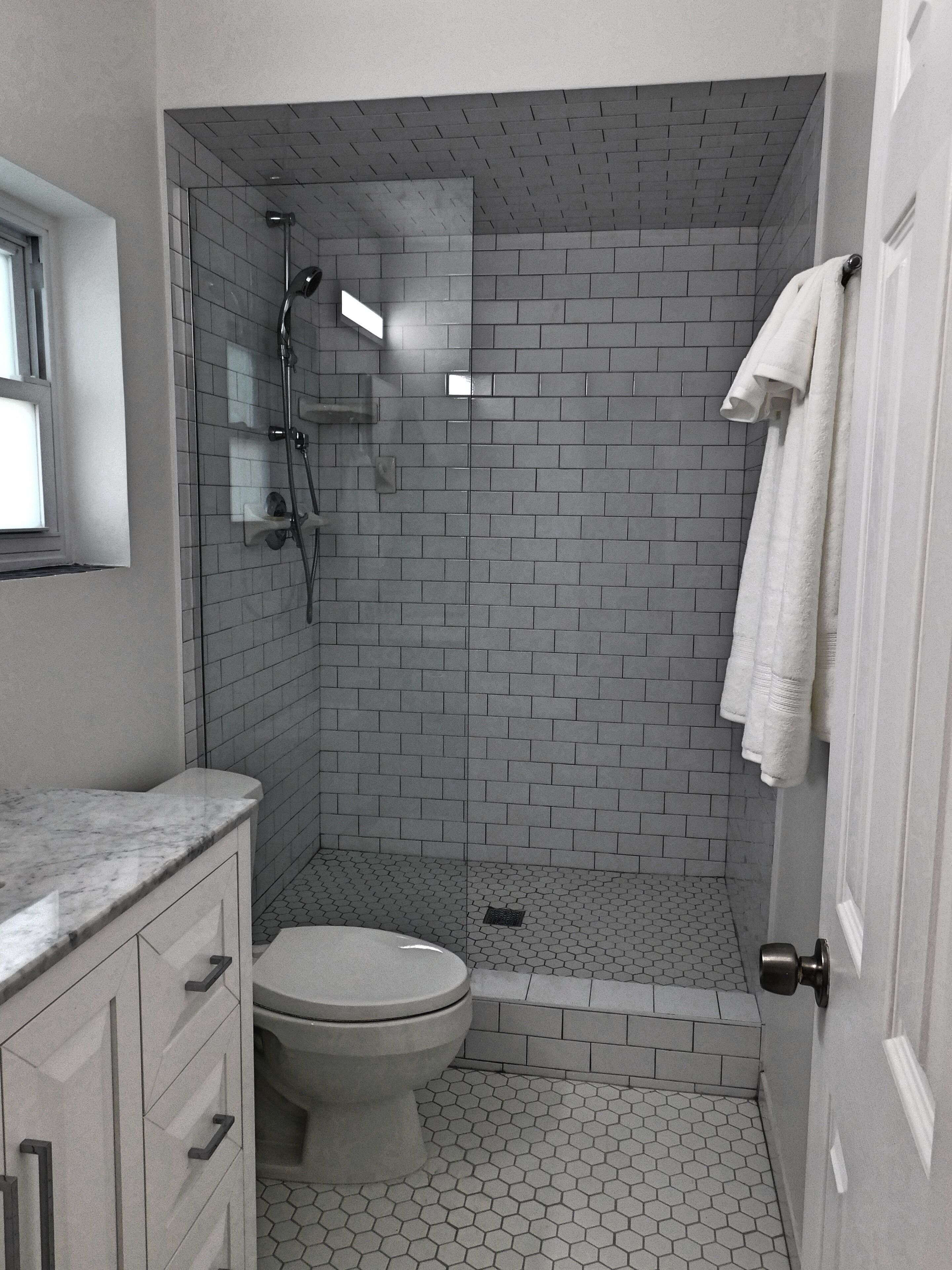 A bathroom with a shower, toilet, and marble countertop.