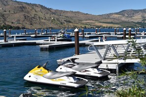 A marina with multiple docks and watercraft, including a yellow and white jet ski. - Welcome to Driftwood Cottage at The Lookout at Lake Chelan (Chelan)