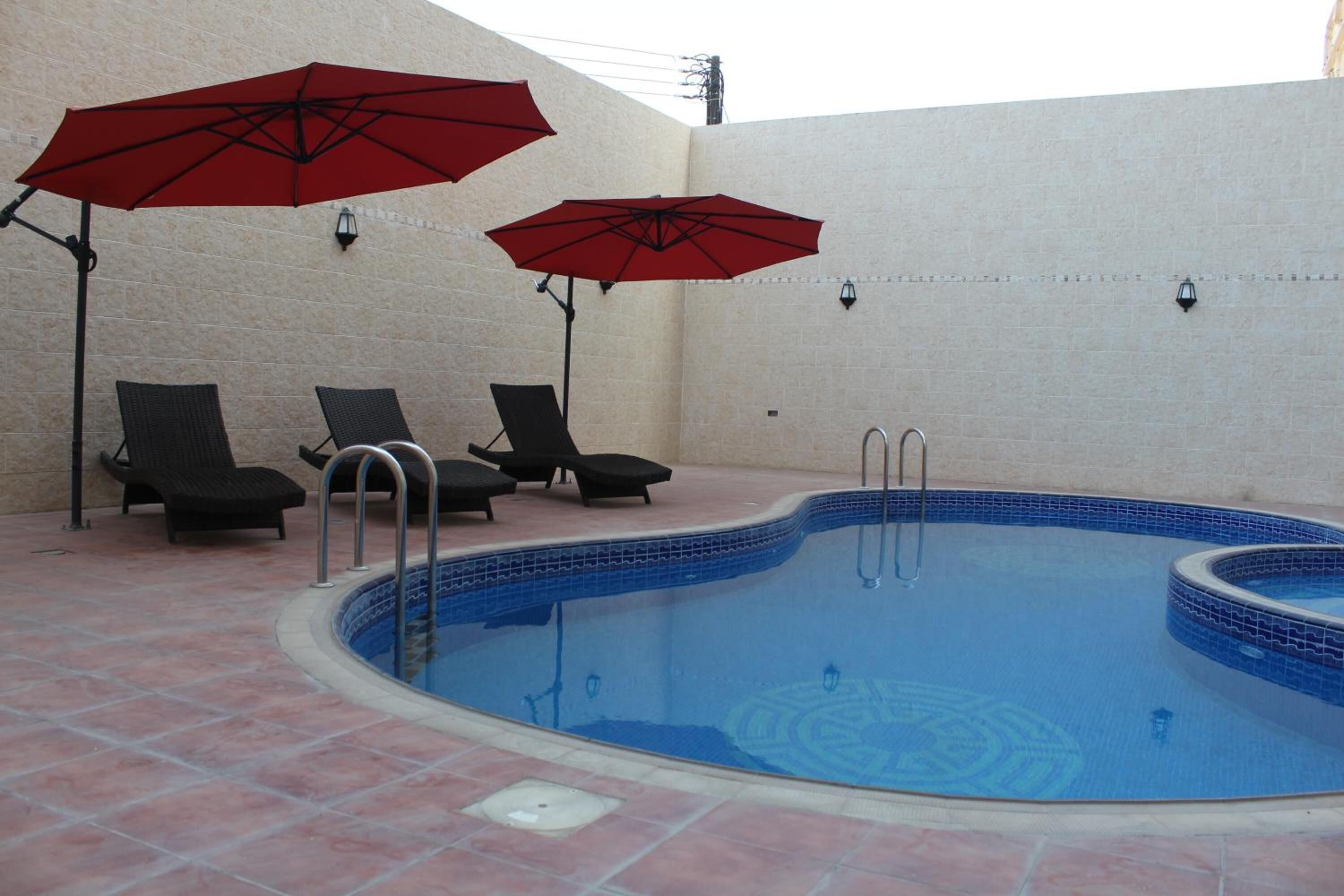 Una piscina con suelo de baldosas y sillas de descanso.