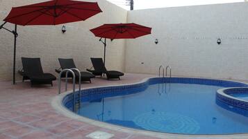 Una piscina con suelo de baldosas y sillas de descanso.