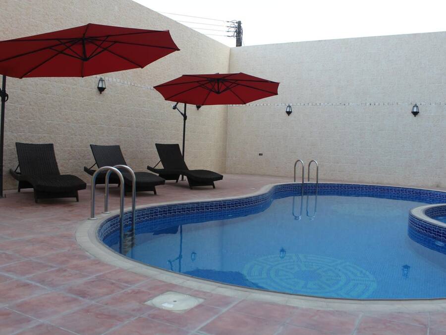 Una piscina con suelo de baldosas y sillas de descanso.
