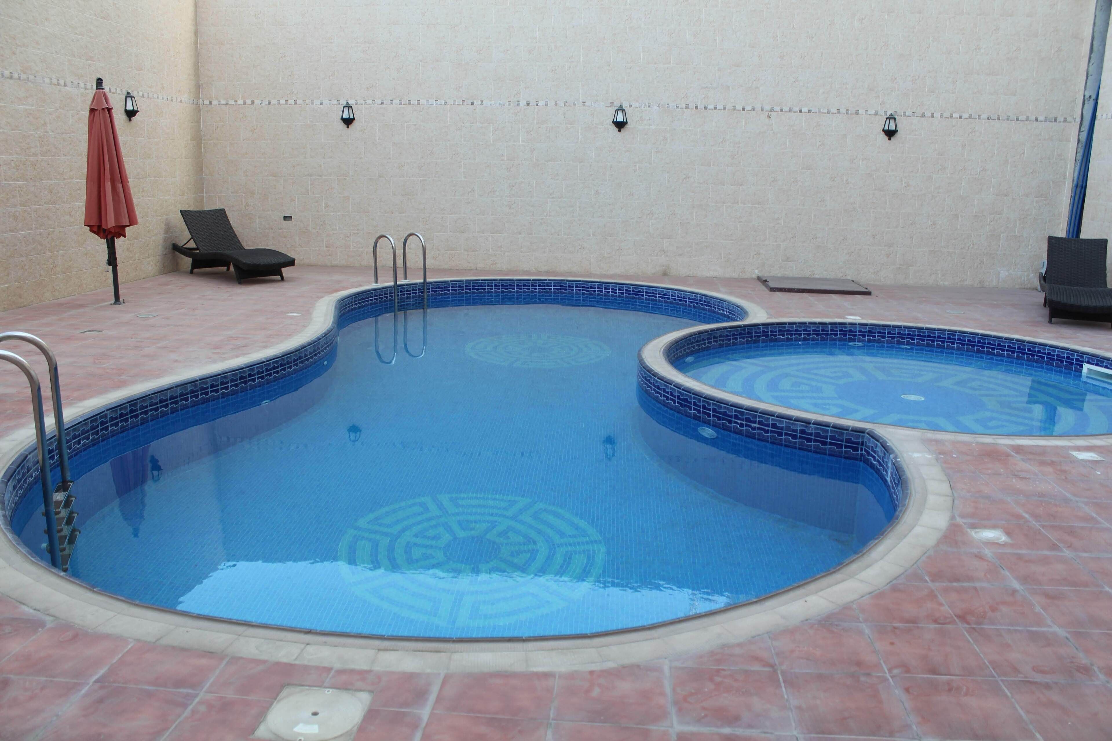 Une piscine divisée en deux zones distinctes, une chaise longue et un parasol.