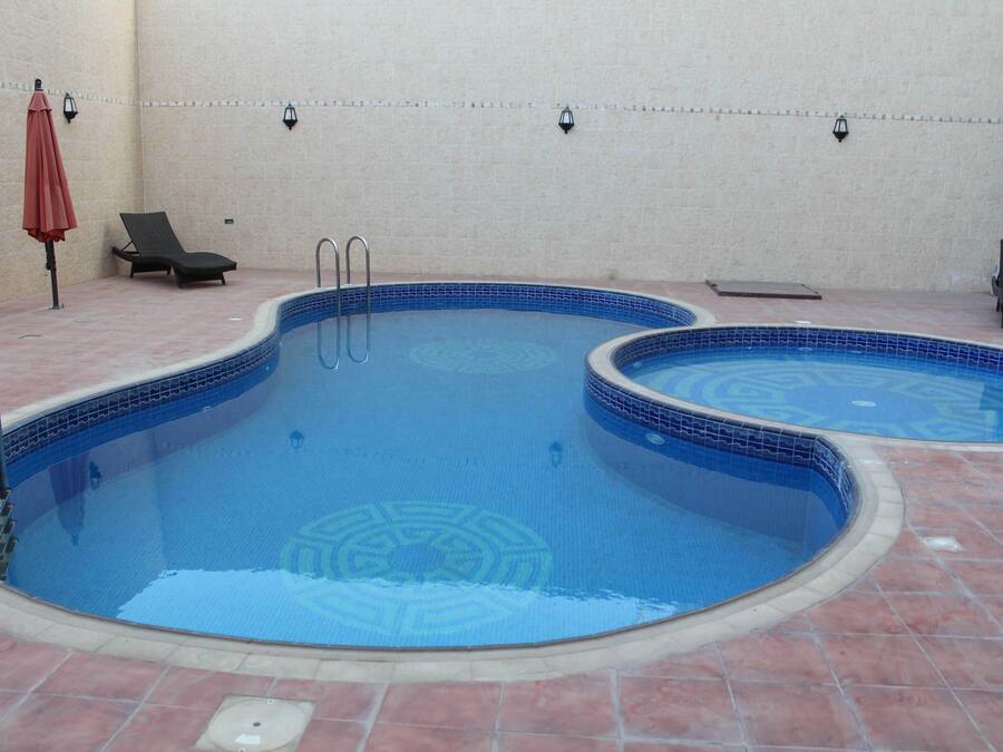 Une piscine divisée en deux zones distinctes, une chaise longue et un parasol.