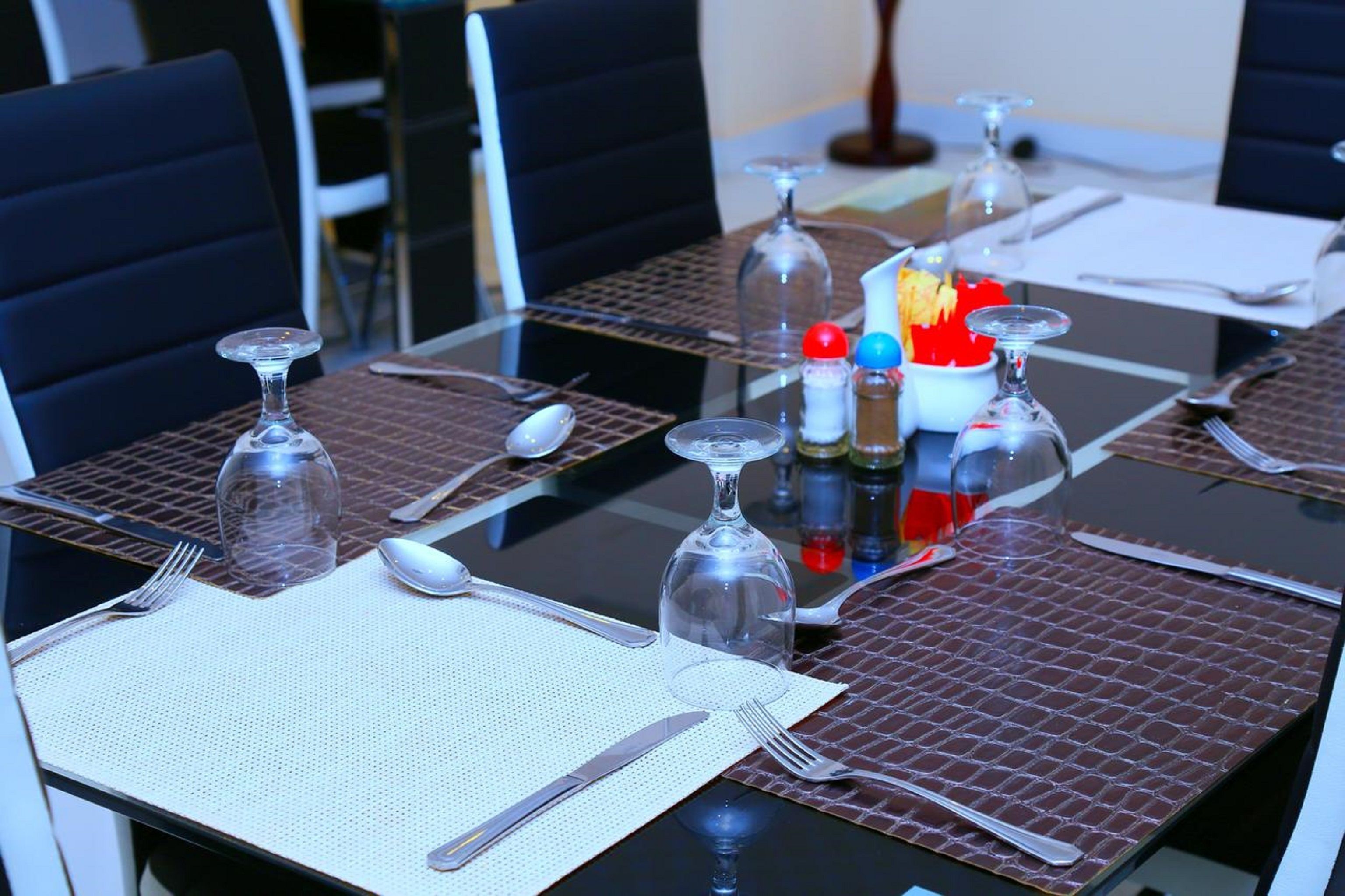 Une table à manger dressée avec des couverts, des verres et des condiments.