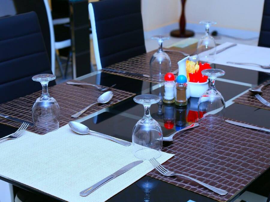 Une table à manger dressée avec des couverts, des verres et des condiments.
