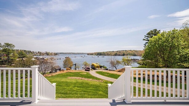 Une terrasse avec vue sur un lac, des bateaux et la végétation environnante.