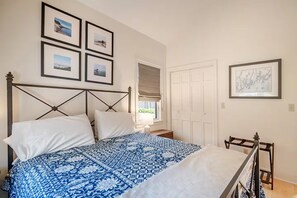 A bedroom with a bed, a bedside table, a wardrobe, and framed pictures on the wall. - Contemporary Cottage With Spectacular Ocean Views And Access (Bristol)