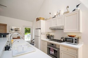A modern kitchen with white cabinets, a stainless steel range, a microwave, and a gas stove. - Contemporary Cottage With Spectacular Ocean Views And Access (Bristol)
