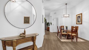A dining area with a round mirror, a glass-top console table, wooden chairs, and a chandelier. - Bahama Bay, Davenport, Florida Oversize 2 Br condo (Davenport)
