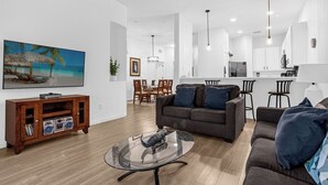 A modern living room with a glass coffee table, a sofa, and a wooden entertainment unit with books and a radio. - Bahama Bay, Davenport, Florida Oversize 2 Br condo (Davenport)
