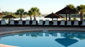 A swimming pool with lounge chairs and umbrellas, surrounded by palm trees and a view of a lake. - Bahama Bay, Davenport, Florida Oversize 2 Br condo (Davenport)