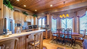 A kitchen with wooden cabinets, a central island, bar stools, and a dining table with chairs.