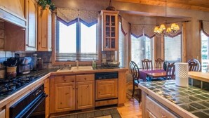 A kitchen with wooden cabinets, a stove, and a dining area with a table and chairs.