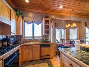 Kitchen features a stove, sink, and dishwasher, with a dining area and central island.