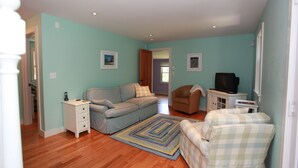 Una sala de estar con sofá, sillones, televisor y un mueble bajo.