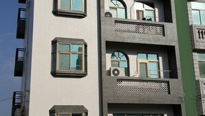 A multi-story building with a modern architectural design, featuring balconies, large windows, and a ground-level entrance.