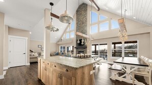 A spacious kitchen with a large island, wooden cabinets, and a stone fireplace.
