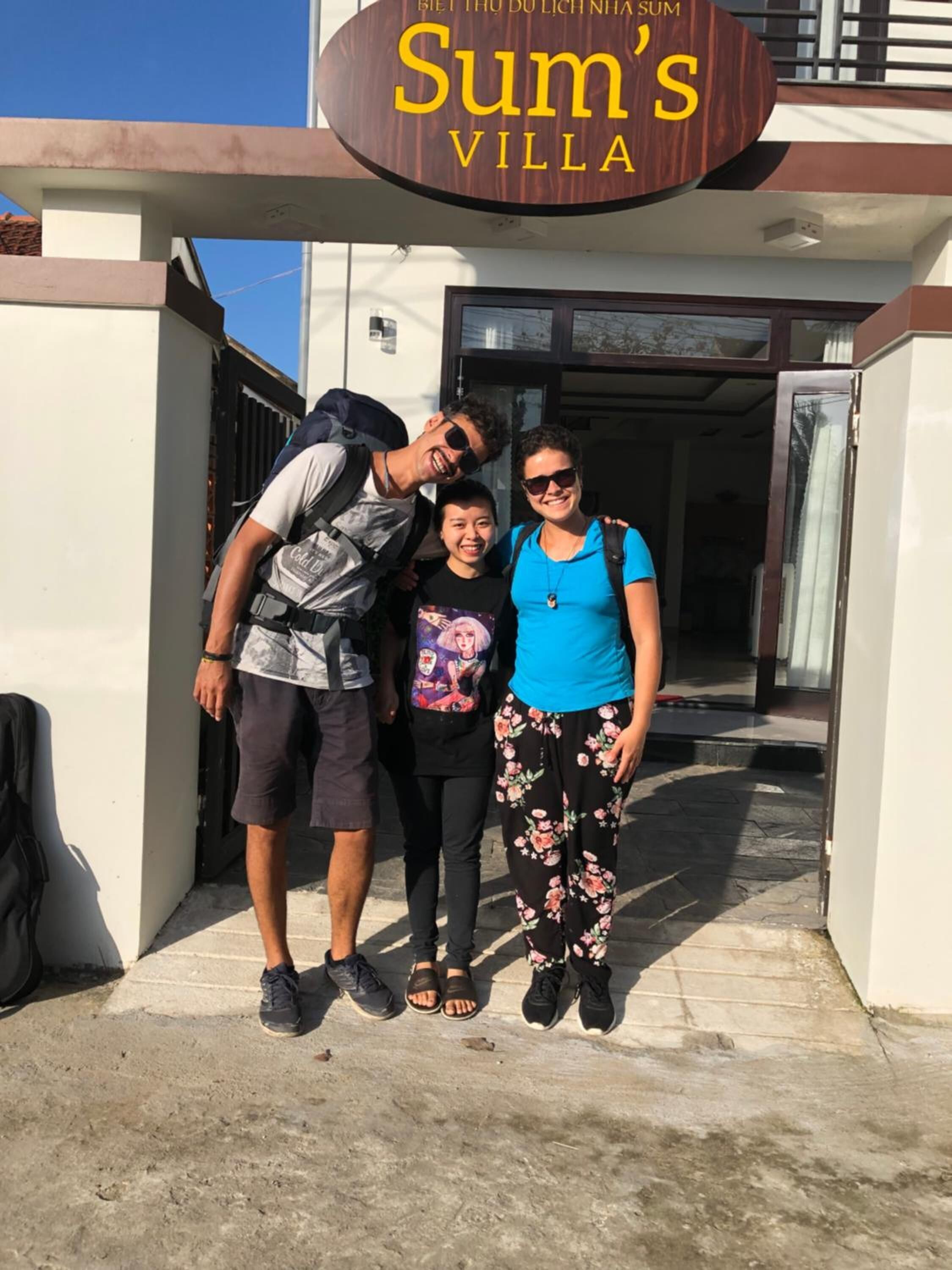 A family standing in front of Sum's Villa, a building with a sign indicating its name.