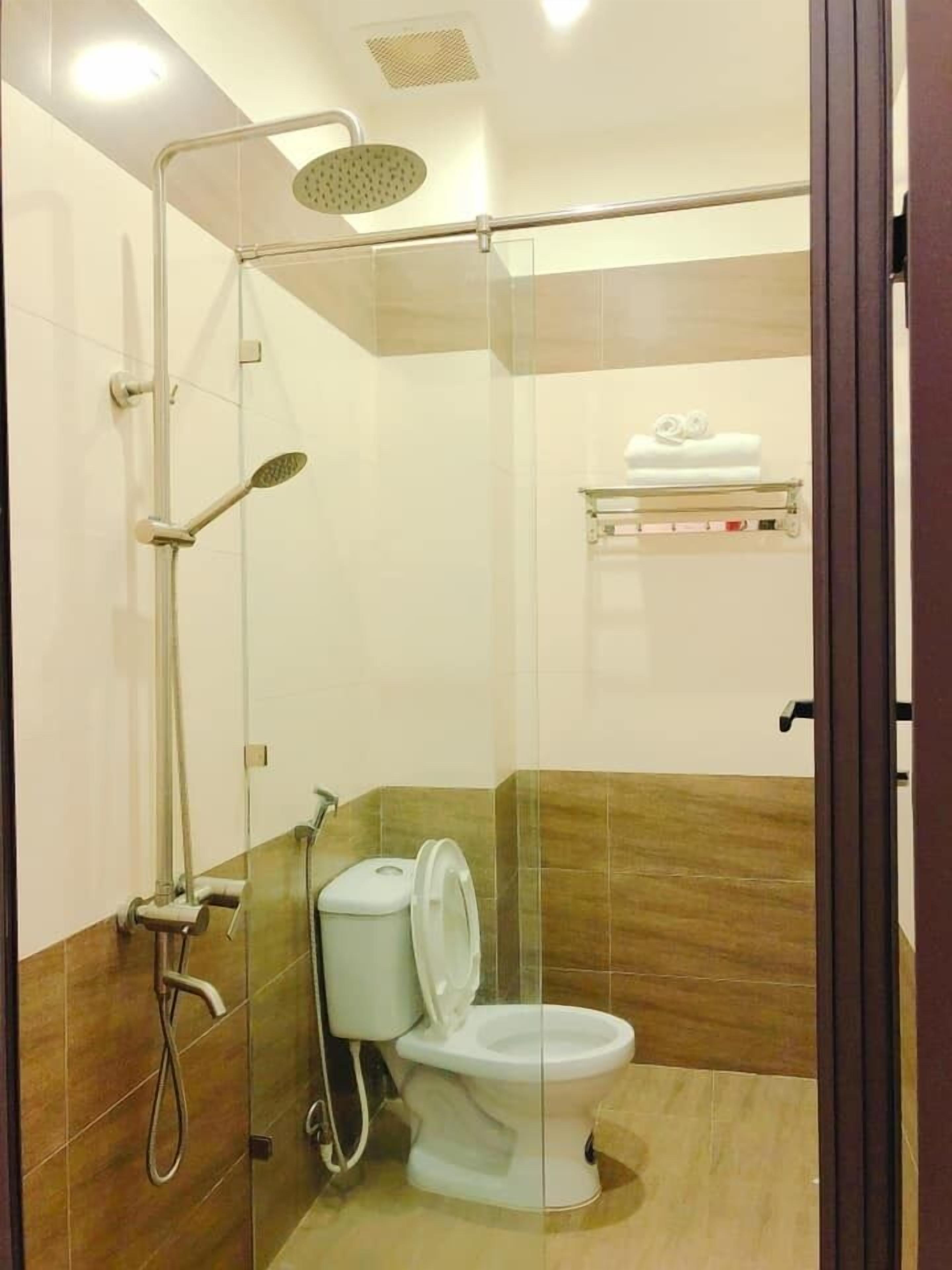 A modern bathroom with a glass-enclosed shower, a toilet, and a towel rack.
