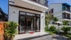 A modern two-story house with a glass entrance, a balcony, and a well-maintained garden. - Sum Villa Hoi An (Da Nang)