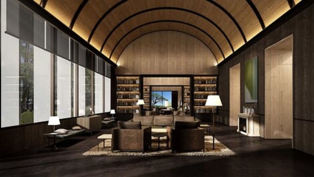 Un interior espacioso y moderno con techo de madera curvada, una zona de estar central con sofás y una mesa de centro, y una amplia estantería llena de libros.